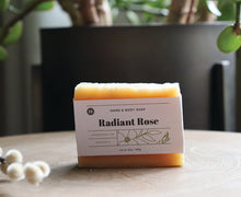 Load image into Gallery viewer, Radiant Rose hand and body soap bar on a stand with a plant. 5 oz, handcrafted, organic. Olive Seed
