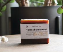 Load image into Gallery viewer, Vanilla Sandalwood hand and body soap bar on stand with plant. handcrafted, organic, vegan. Olive Seed
