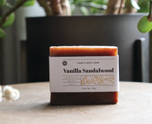 Load image into Gallery viewer, Vanilla Sandalwood hand and body soap bar on stand with plant. handcrafted, organic, vegan. Olive Seed