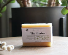 Load image into Gallery viewer, The Hipster hand and body soap bar on a stand with a plant. handcrafted, organic, vegan. Olive Seed
