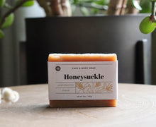 Load image into Gallery viewer, Honeysuckle face and body soap bar on a table with plant. handcrafted, vegan. Olive Seed
