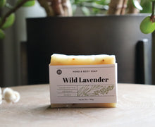 Load image into Gallery viewer, Wild Lavender hand and body soap bar on a table near a plant. handcrafted, organic, vegan. Olive Seed
